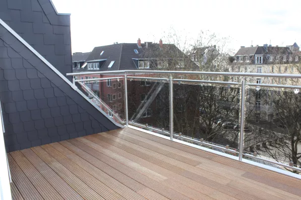 Einen Balkon mit einem Edelstahlbalkongeländer mit dunklem Glas.
