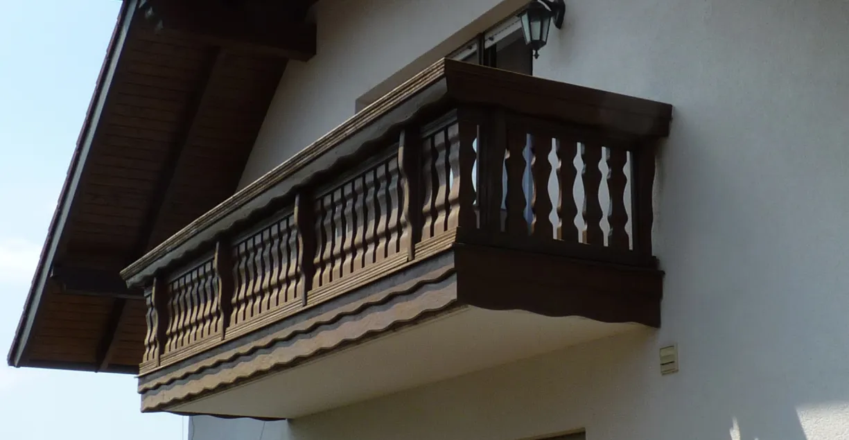 Einem Balkon dessen Balkongeländer aus Holz ist.