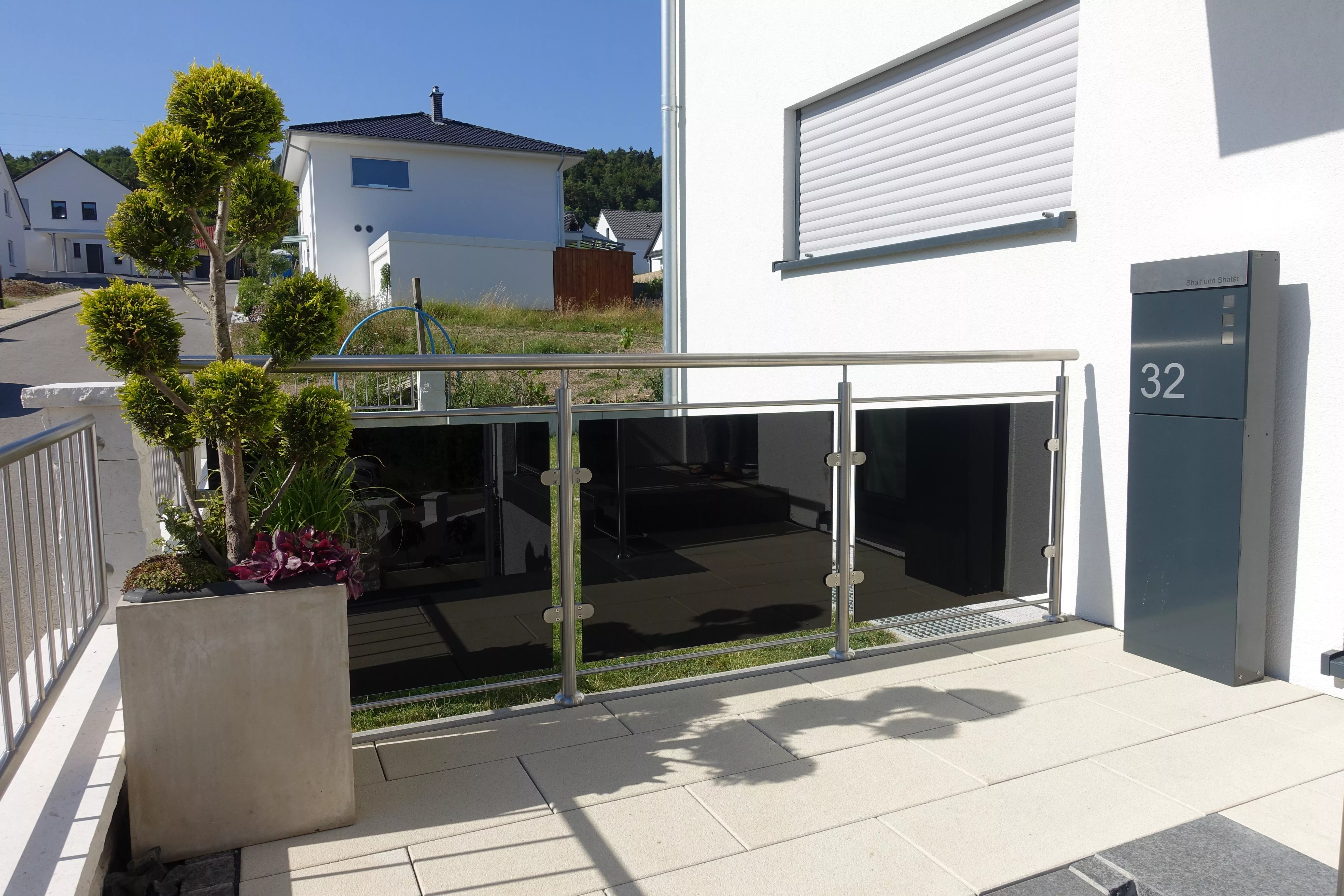 Eine Terrasse mit Sichtschutz aus Edelstahl und schwarzem Glas.